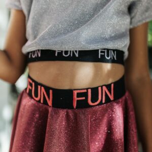A close-up of a child wearing a glittery top and skirt, exuding fun fashion vibes.