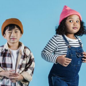 Playful children in stylish casual attire posing against a vibrant blue background.