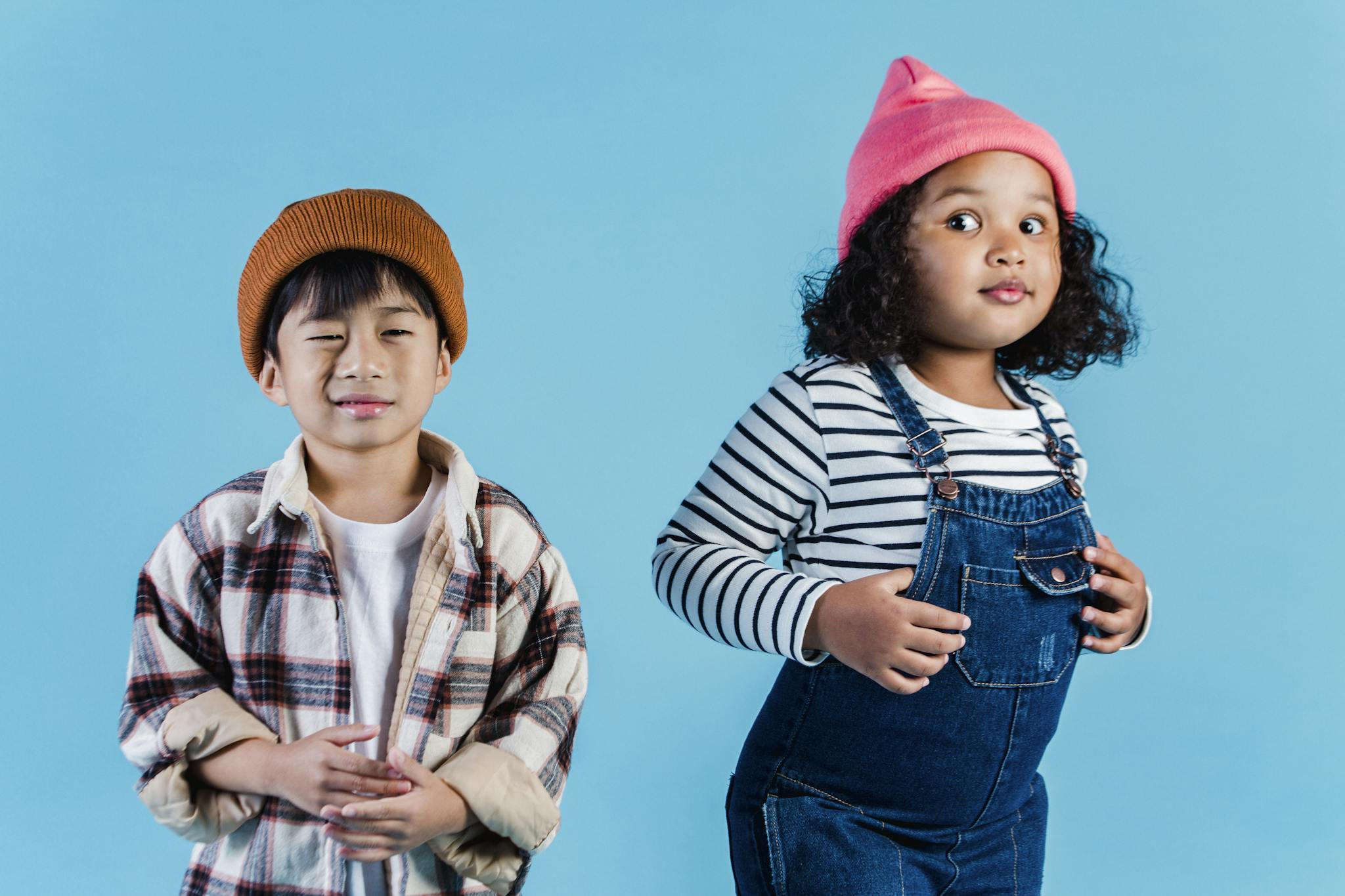 Playful children in stylish casual attire posing against a vibrant blue background.